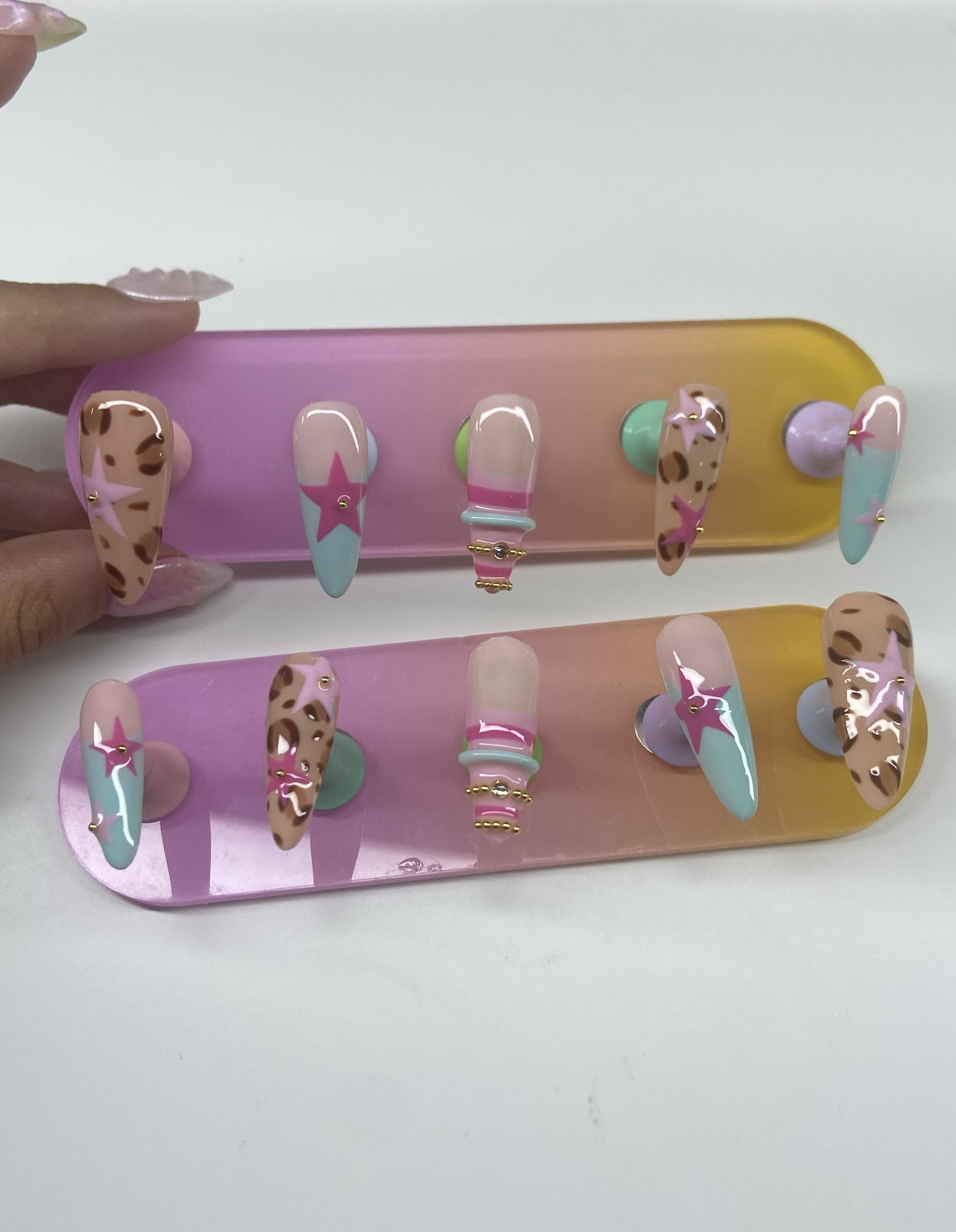 Two nail tips displays with hand-painted leopard and star press-on sets in progress